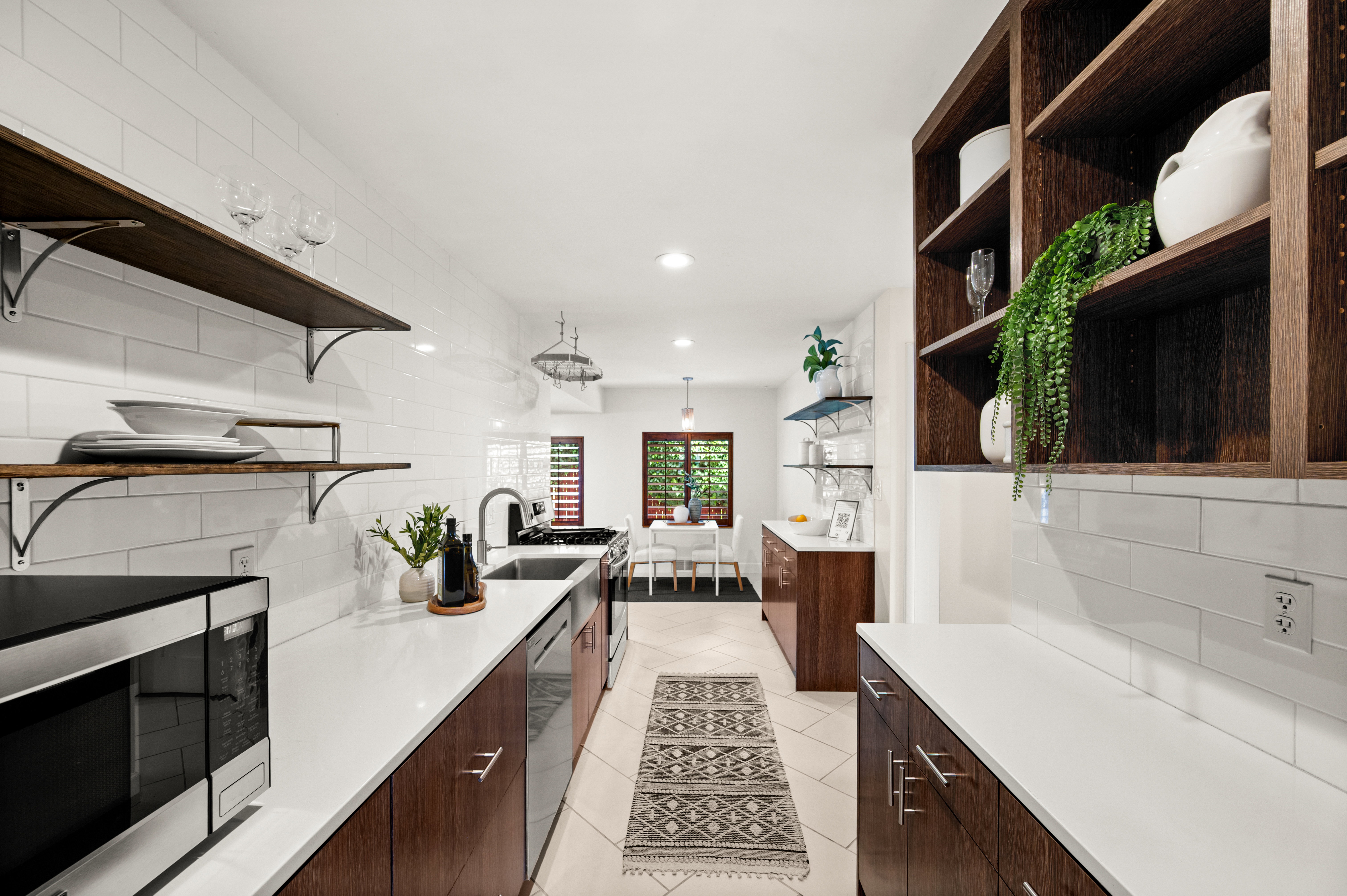Galley-style kitchen featuring white subway tile backsplash, white countertops, and wood-finish cabinetry