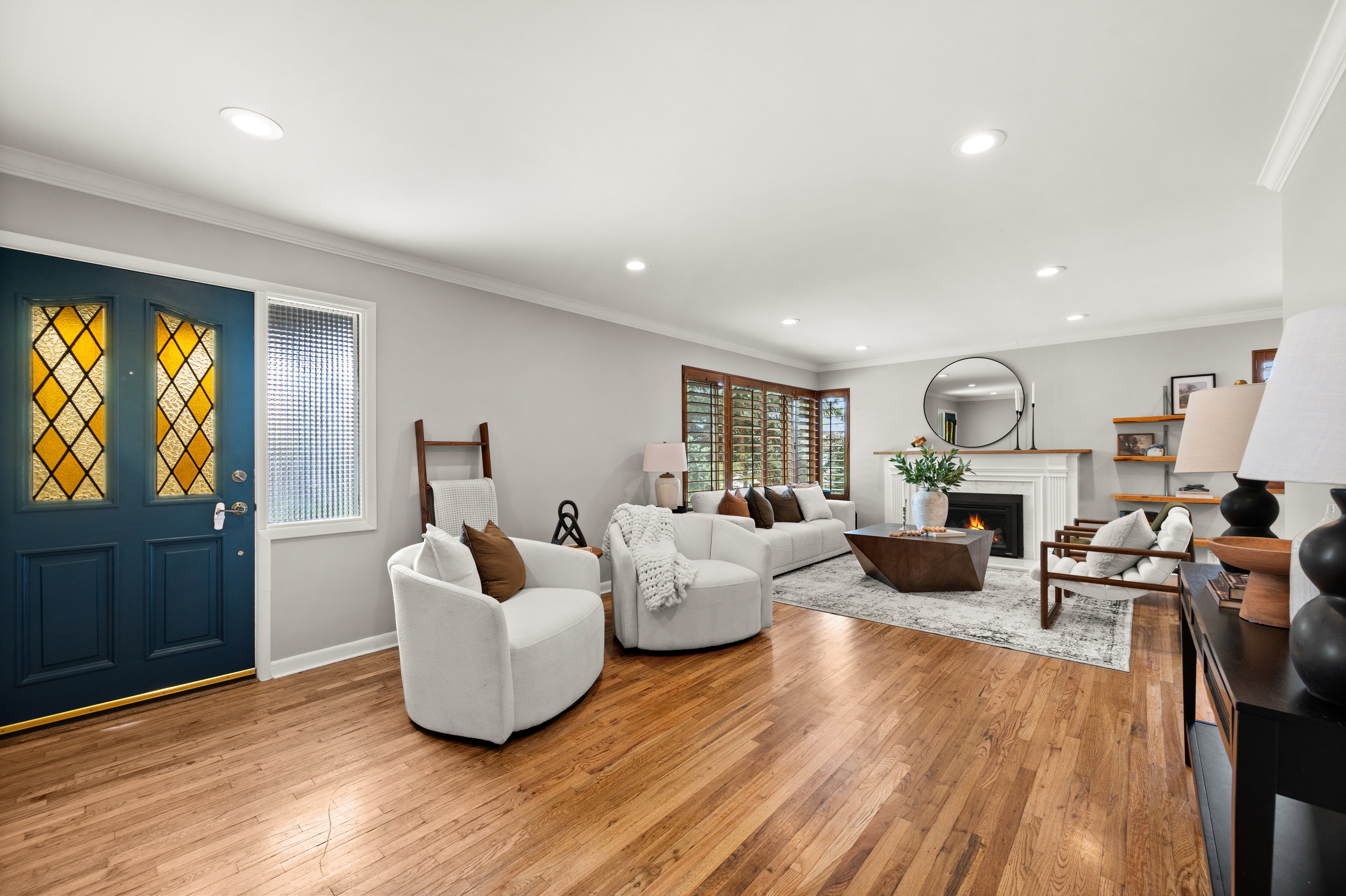 Living room featuring wood-finish flooring, recessed lighting, and a white fireplace with a dark surround