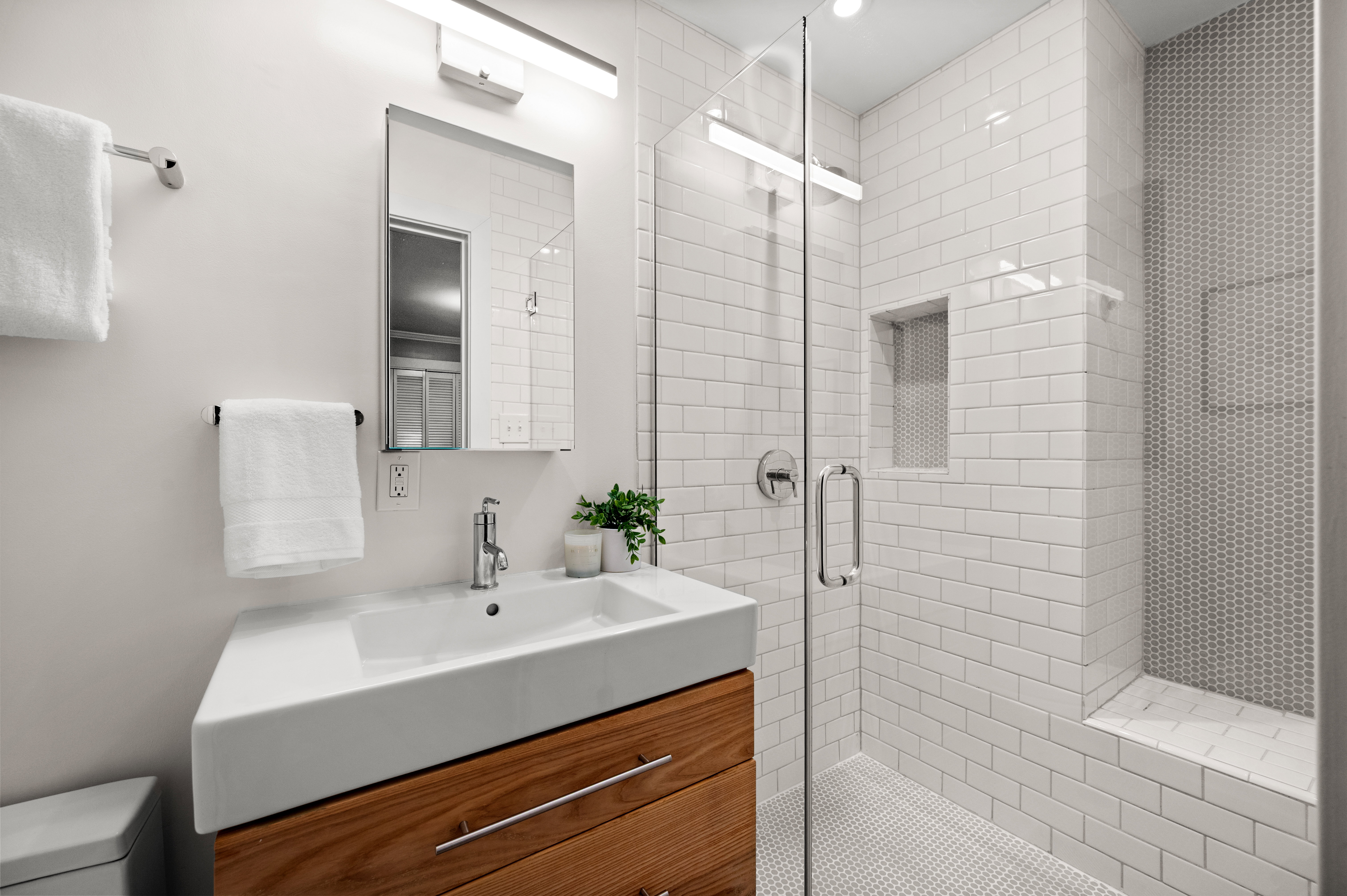 Modern bathroom featuring a wood-finish vanity with an integrated white sink and polished chrome faucet