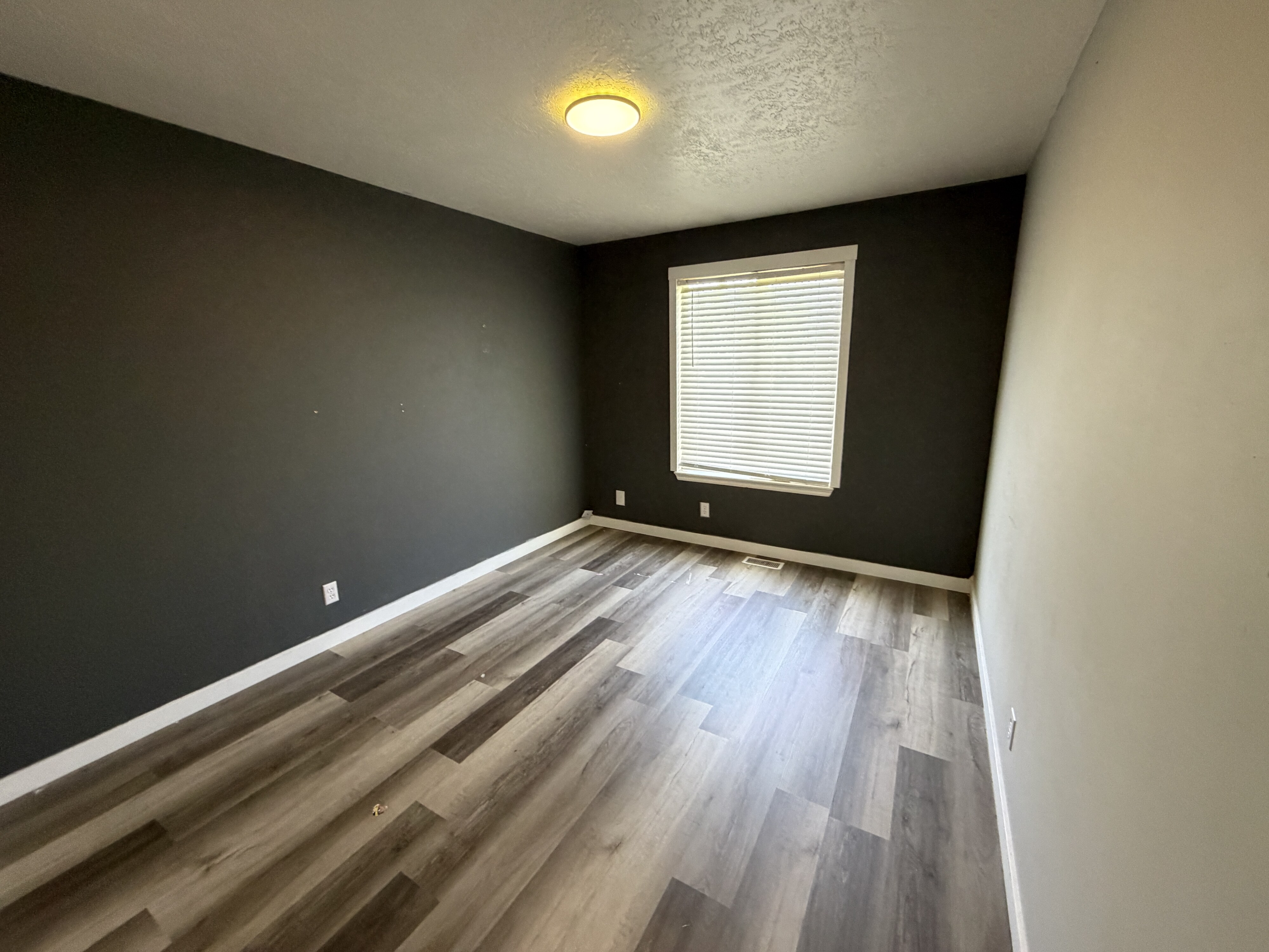 Interior space featuring wood-finish flooring, a window with blinds, and contrasting wall colors