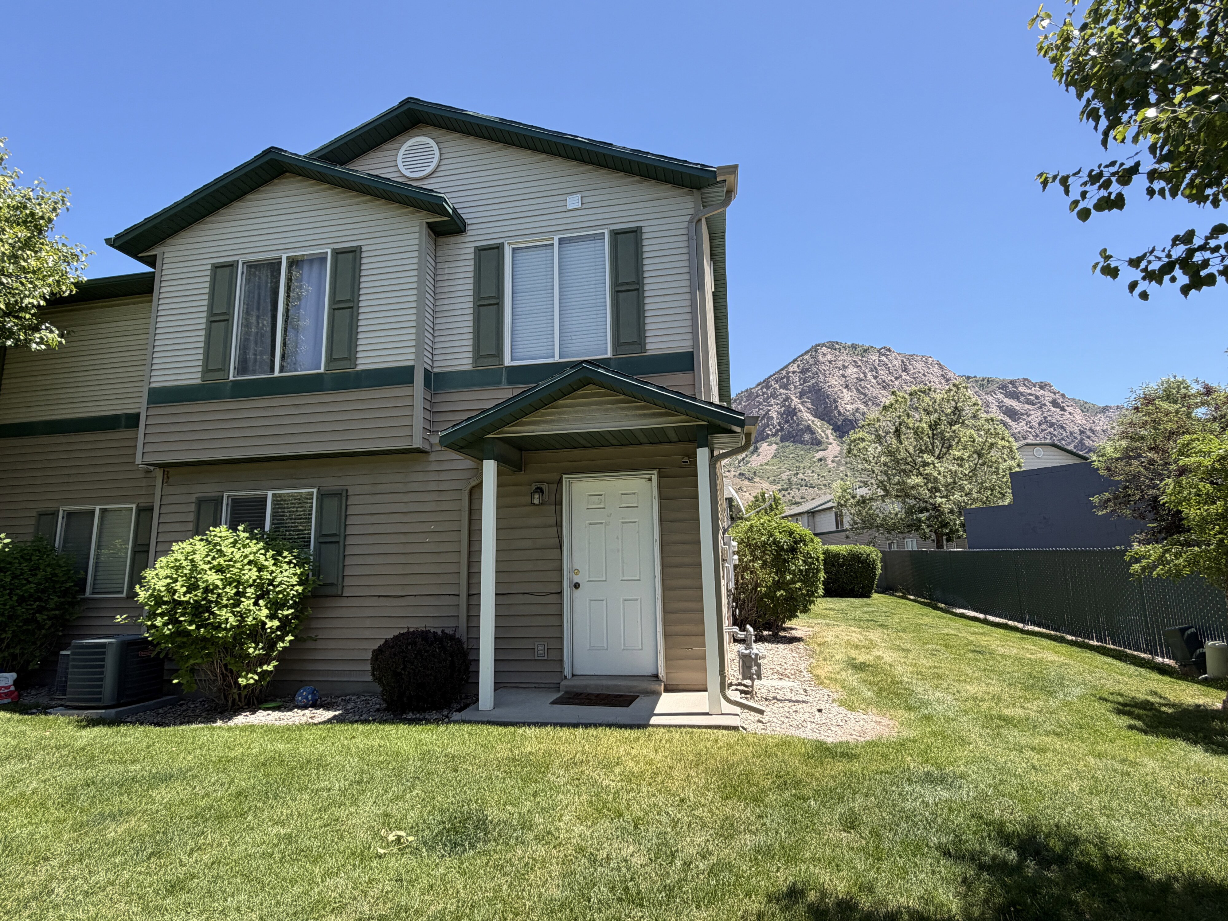 Two-story residence featuring light and dark neutral siding, a covered entry, and green window shutters