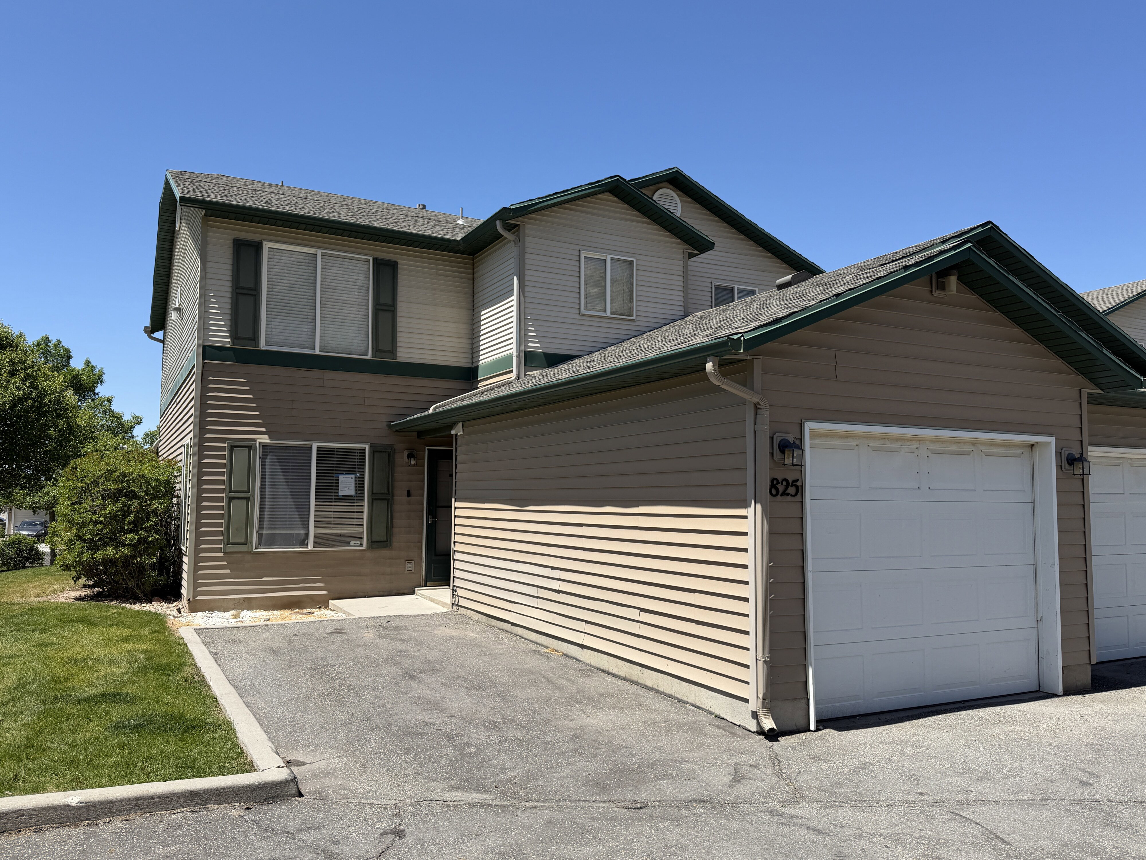 Two-story townhouse with beige siding and dark green trim
