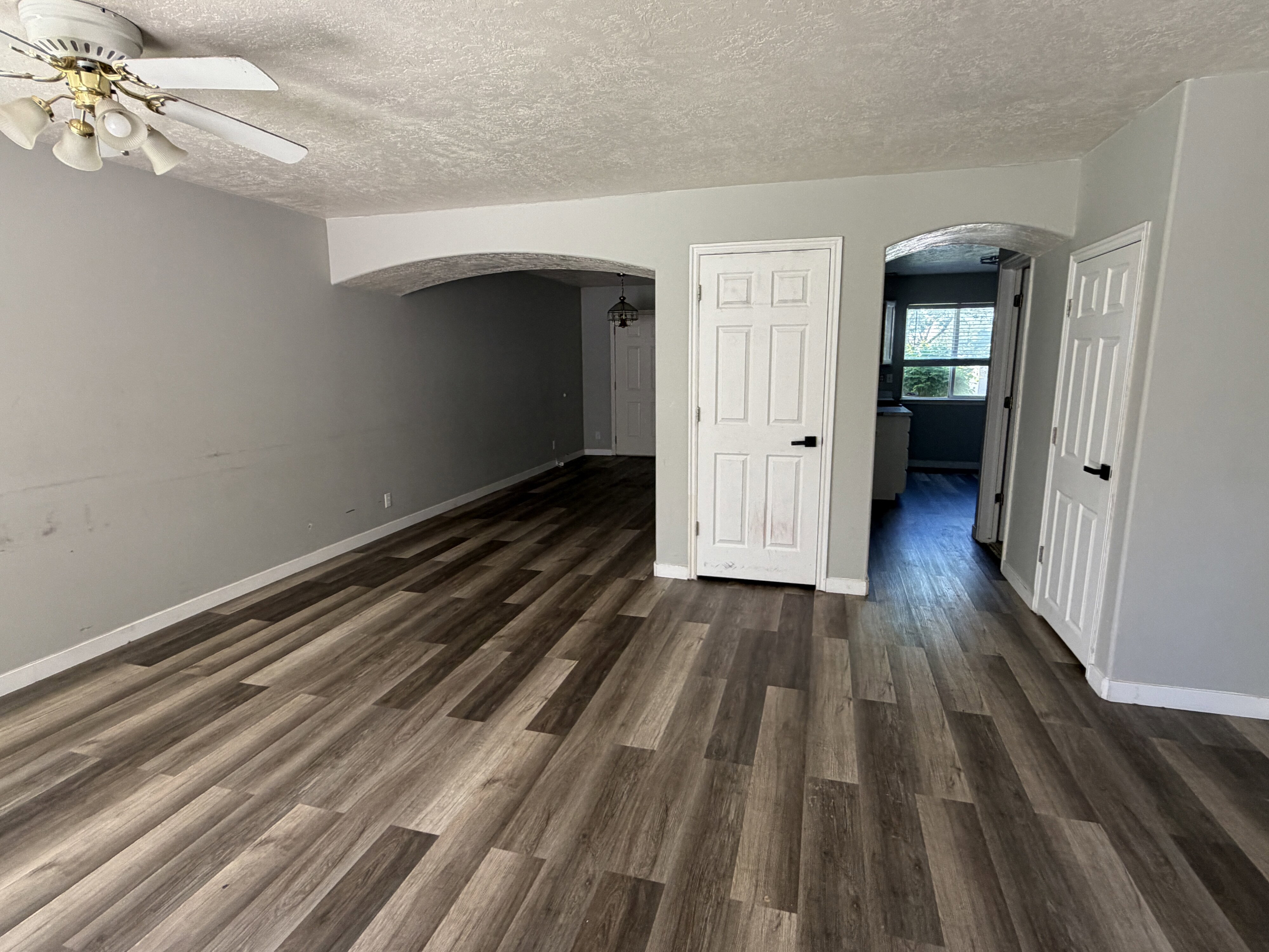 Spacious room featuring wood-finish flooring, light gray wall paint, and white trim