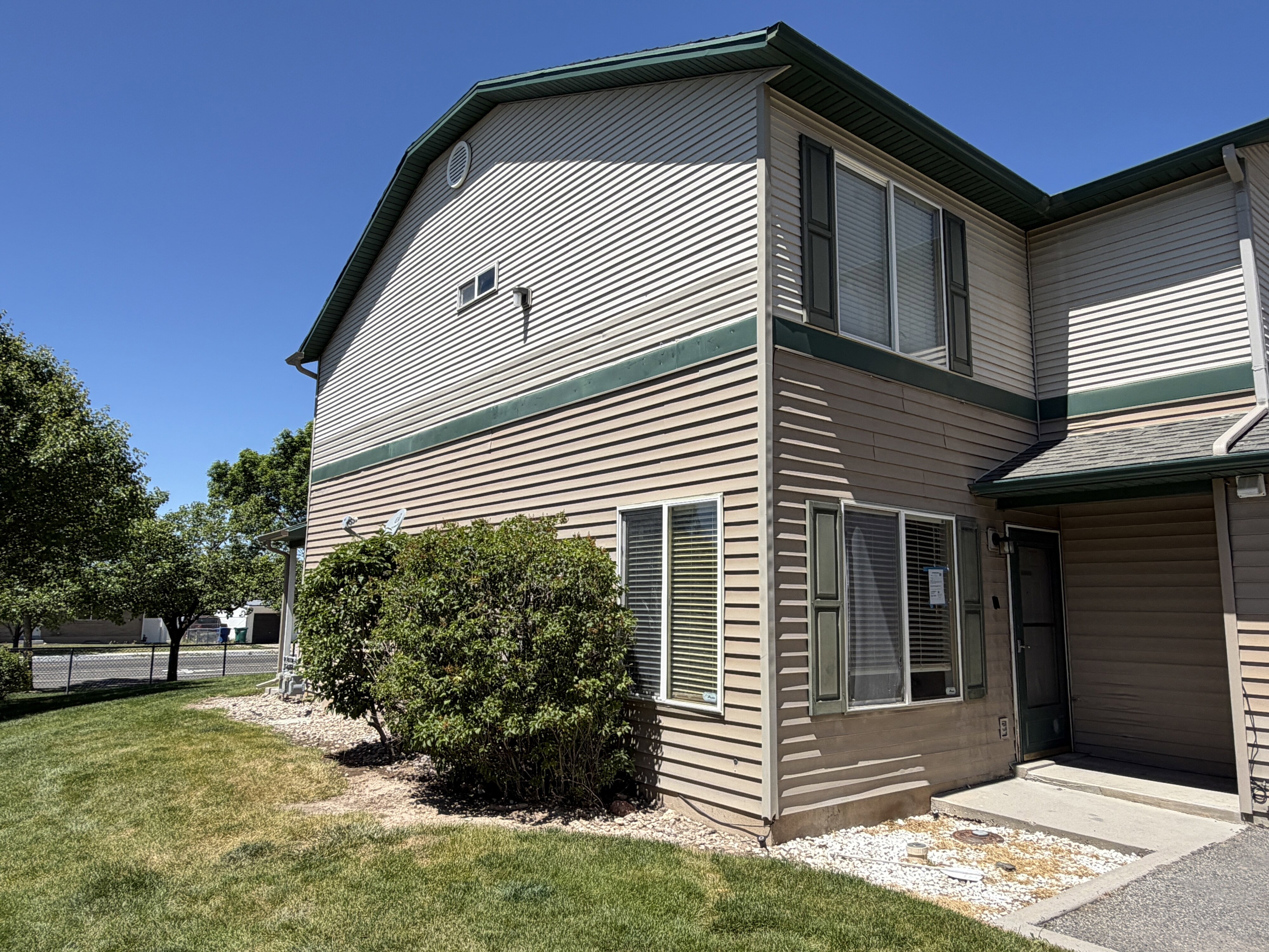 Multi-level exterior with horizontal siding in two tones, dark green trim, and a dark shingle roof
