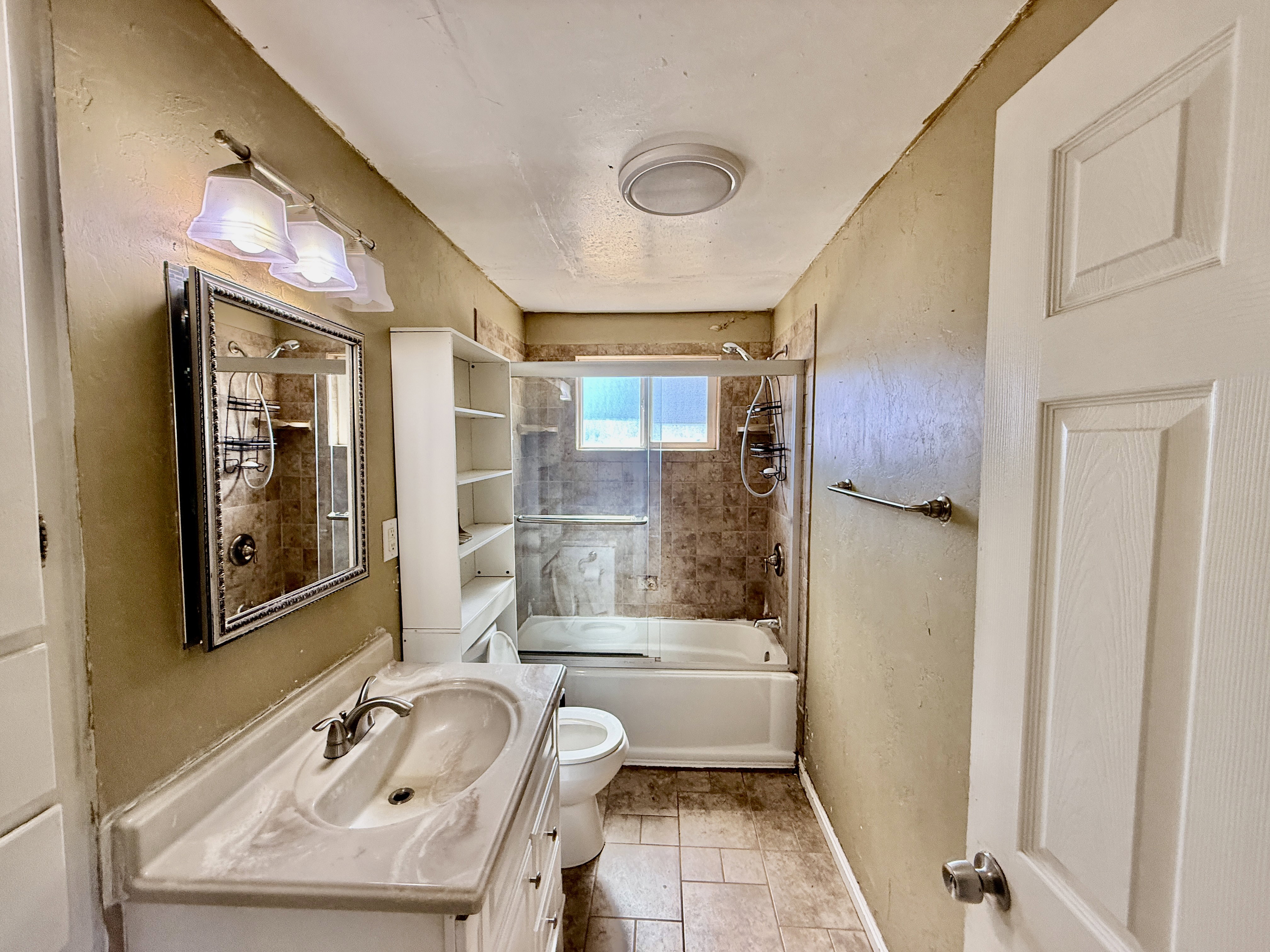 Bathroom featuring a combination tub/shower with tiled surround and glass enclosure
