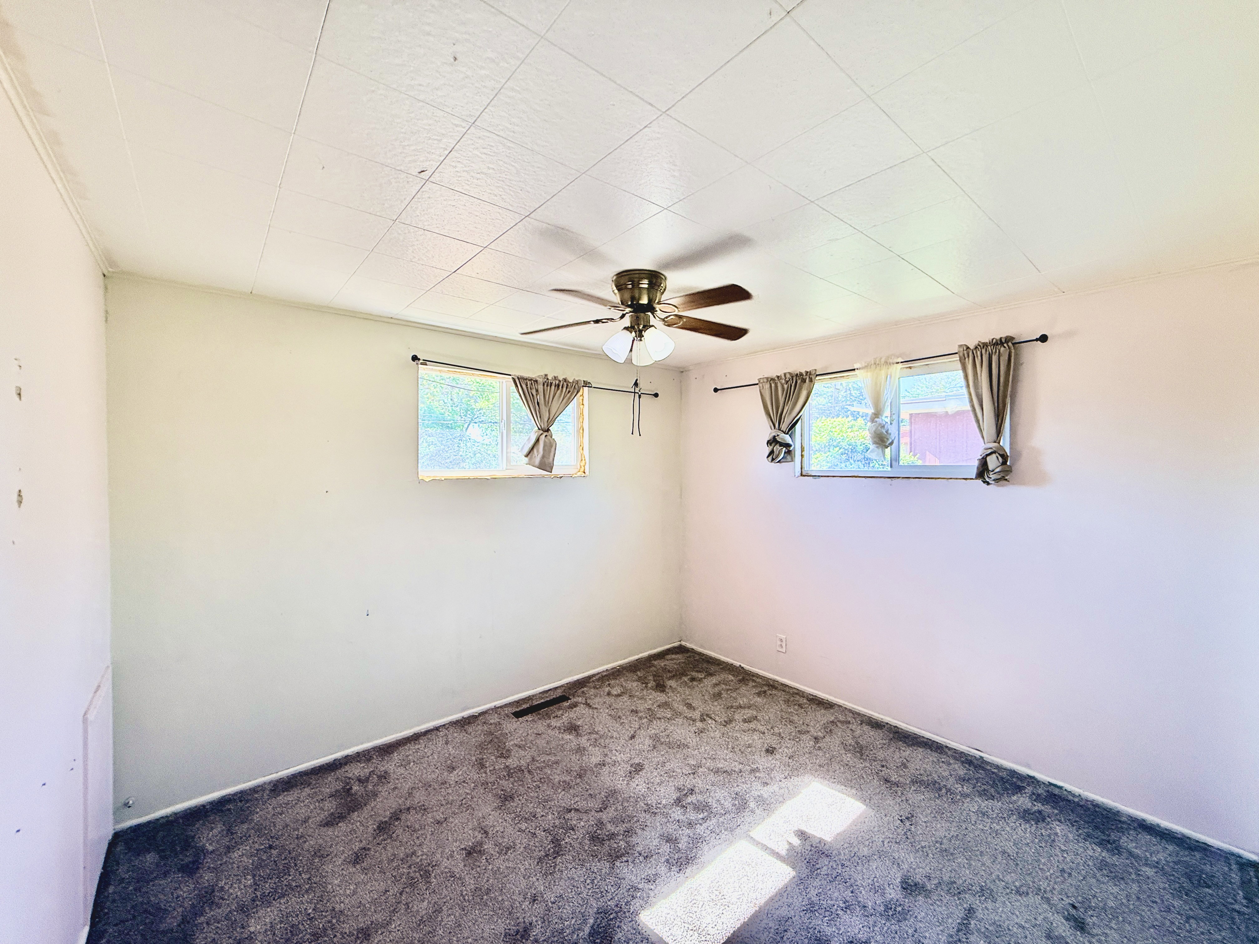 Carpeted room with a ceiling fan light fixture