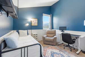 Room featuring a window, blue painted walls, and white wainscoting