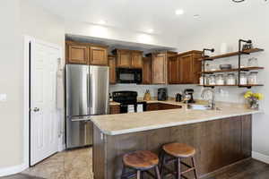 Contemporary kitchen featuring wood cabinetry, stainless steel appliances, and a peninsula with countertop seating