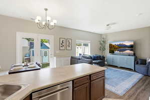 Open-concept living space featuring wood-finish flooring, a kitchen island with integrated sink and dishwasher, and French patio doors leading to the exterior
