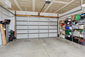 Spacious garage featuring a paneled overhead door, concrete flooring, and overhead rafters for storage