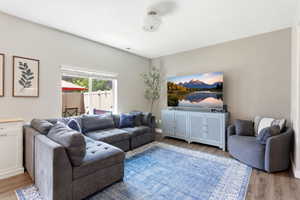 Living area featuring wood-finish flooring, a large window, and a built-in white cabinet with a light-toned countertop