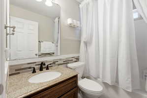 Bathroom featuring a single vanity with a granite countertop, undermount sink, and dark bronze faucet