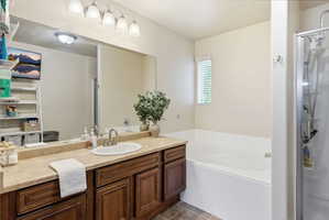 Bathroom featuring a dark wood-finish vanity with a single basin sink, spacious countertop, large mirror, and overhead vanity lighting