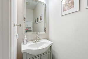 Half bath featuring a vanity with an integrated white sink, brushed nickel faucet, a framed mirror, and light-toned wallpaper