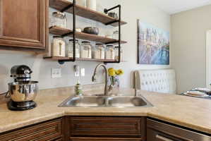 Corner stainless steel double basin sink with a high-arc faucet, set within a neutral-toned countertop