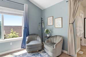 Bright room featuring a large window with white blinds, a vaulted ceiling, and light blue walls
