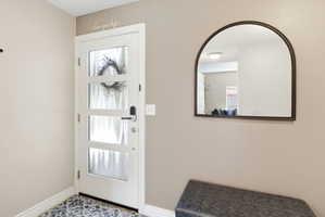 Entryway featuring a white door with frosted glass panels, an arched mirror, and patterned floor tile