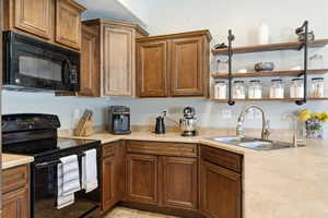 Kitchen featuring abundant wood cabinetry, an integrated microwave, a built-in range, a double basin stainless steel sink, and open shelving with industrial-style supports