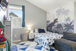 Bedroom featuring a decorative wall mural, a single window, and a geometric pattern area rug