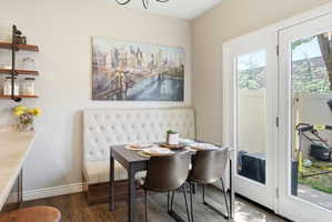 Dining area featuring a tufted banquette, wood-finish flooring, and French doors providing exterior access