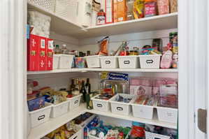 Pantry featuring white built-in shelving, white walls, and a white door frame