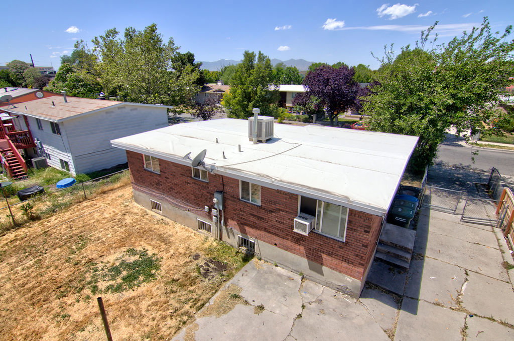 Brick exterior building featuring a flat white roof, multiple windows, and exterior HVAC units
