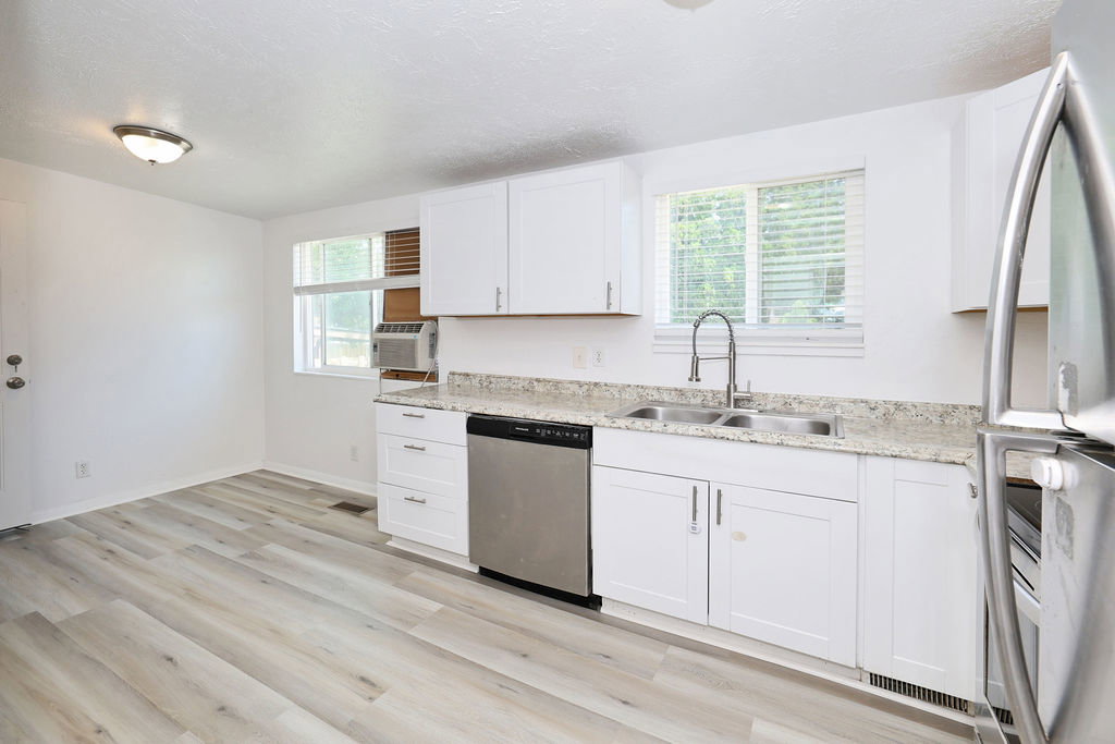 Kitchen featuring white cabinetry, granite-finish countertops, stainless steel appliances, and wood-finish flooring