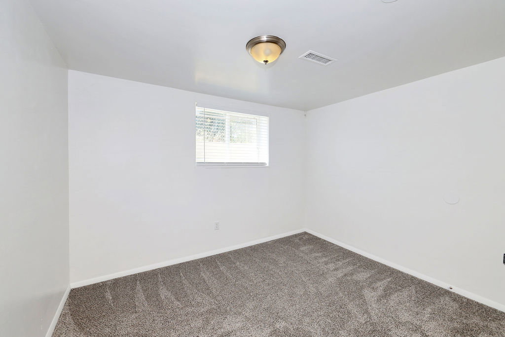 Room featuring white painted walls, gray patterned carpet, and a single window with horizontal blinds