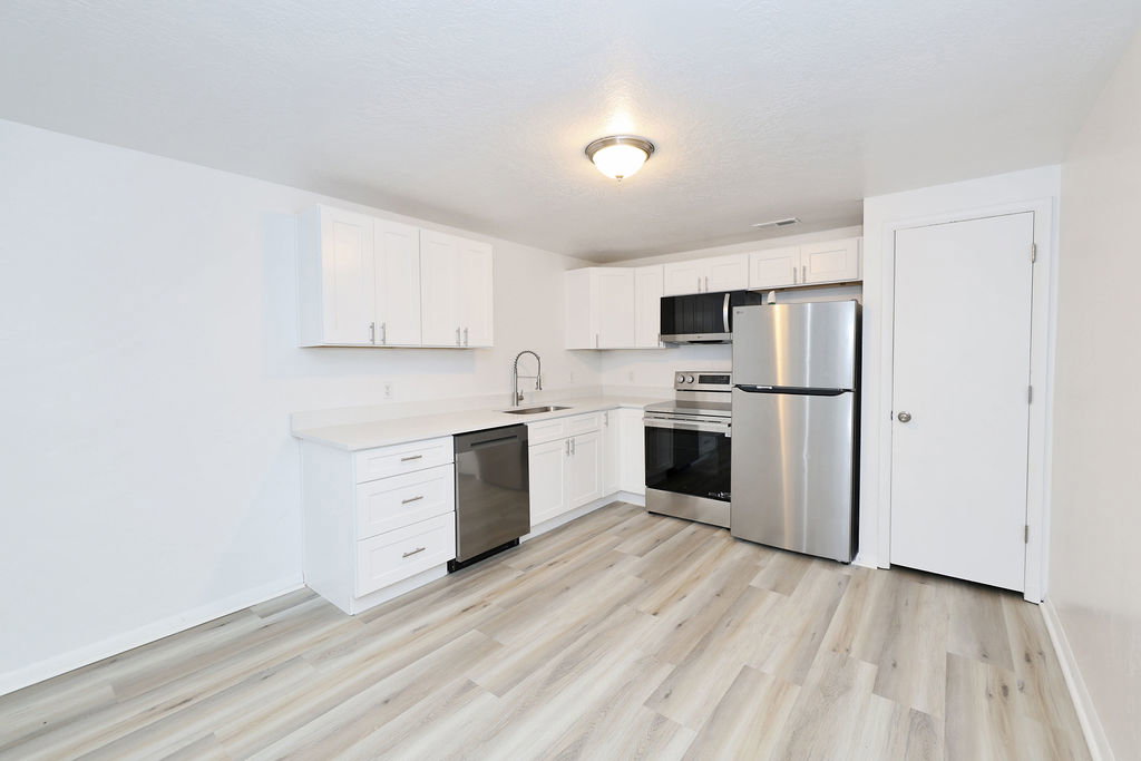 Modern kitchen featuring white cabinetry, light-toned wood-finish flooring, and stainless steel appliances