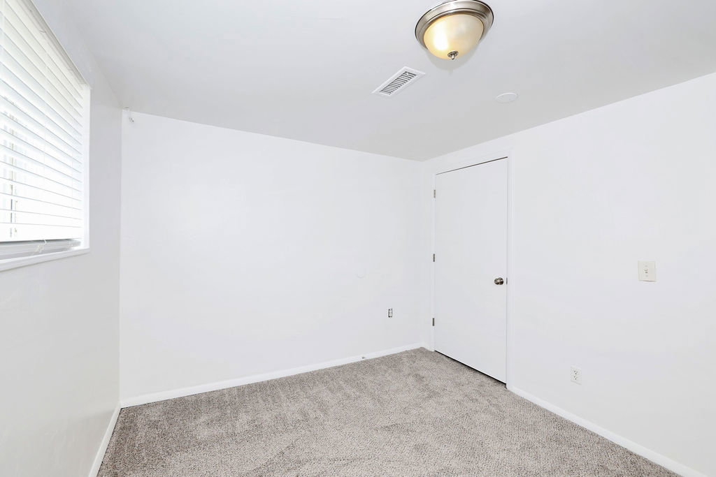 Room featuring light gray carpet flooring, white walls, and a window with blinds