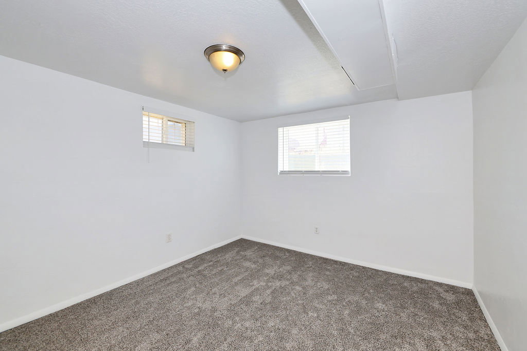 Carpeted room featuring white walls and a ceiling-mounted light fixture
