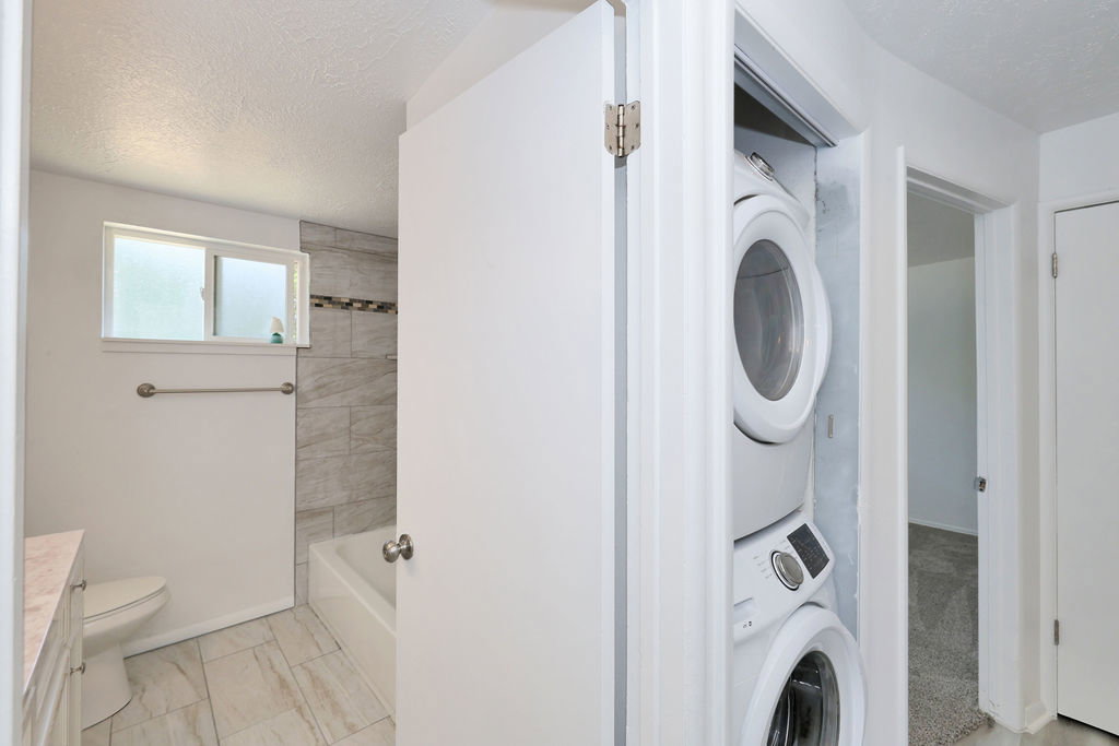 Full-sized stacked laundry units within a dedicated closet, providing convenient access