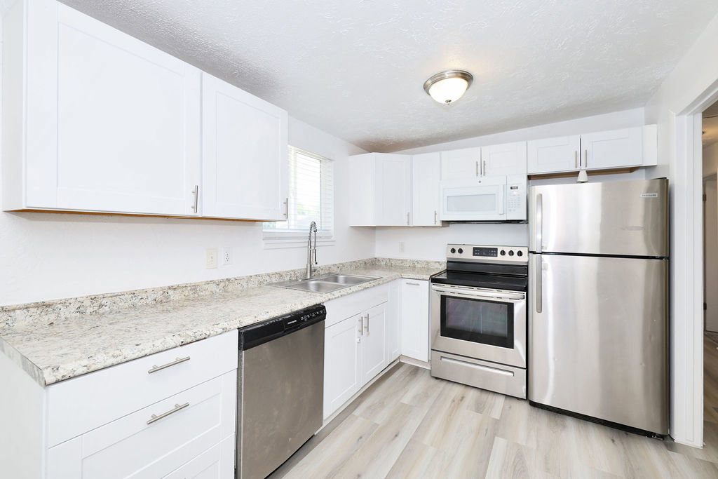 White cabinetry and light wood-finish flooring define this kitchen