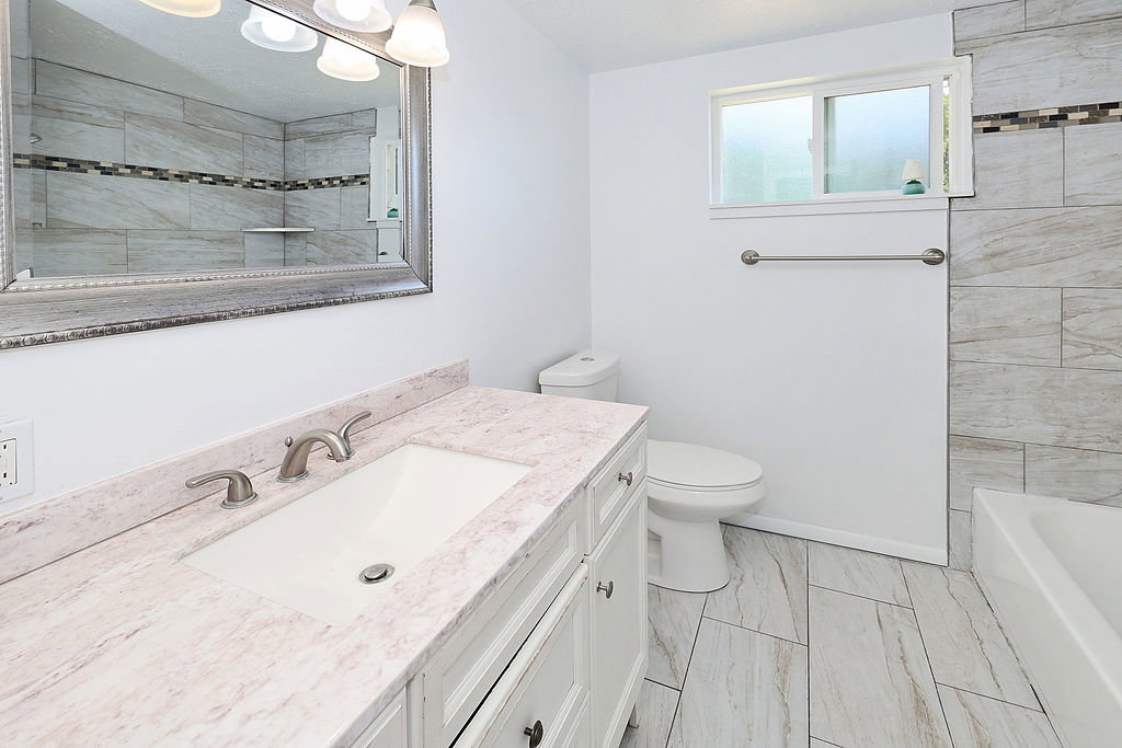 Bathroom featuring a white vanity with an undermount sink, a light-toned countertop, and brushed nickel fixtures
