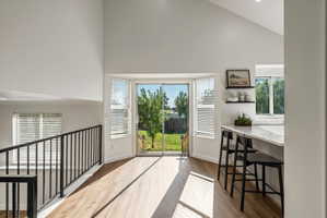 Open-concept interior featuring vaulted ceilings, wood-finish flooring, and a modern kitchen island with a light-toned countertop