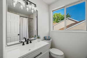 Main Bathroom featuring a rectangular mirror, a vanity with an integrated sink and matte black faucet, and a dual-flush toilet