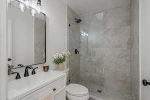 Primary Bathroom featuring a walk-in shower with glass enclosure, large format tile walls, and pebble-style shower floor