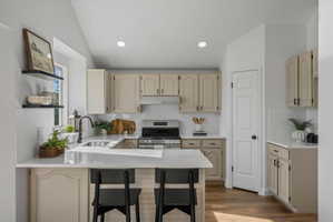 Bright kitchen featuring an L-shaped countertop, a breakfast bar, white subway tile backsplash, recessed lighting, and wood-finish flooring