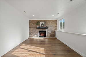 Brick-faced fireplace with a dark mantel, wood-finish flooring, recessed lighting, crown molding, and a window with blinds