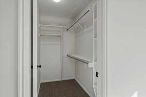 Primary Walk-in closet featuring white shelving, multiple hanging rods, and recessed lighting