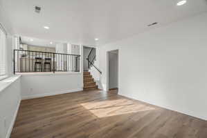 Open concept living space featuring wood-finish flooring, recessed lighting, and white walls