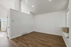 Spacious room featuring vaulted ceilings, wood-finish flooring, recessed lighting, and a built-in window seat