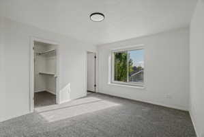Primary Carpeted room with white walls, a single window, and a built-in closet featuring shelving and a hanging rod