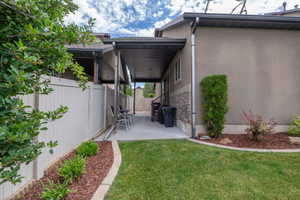 Another view of the covered patio showing the depth of the space and the well-landscaped yard beyond. Great outdoor living space with privacy fencing on both sides.