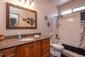 Well-appointed full bath with rich knotty alder cabinetry, granite countertop, framed mirror, and tub/shower combo. Clean, functional, and full of character.