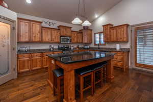 Another gorgeous look at this kitchen, showcasing the full run of knotty alder cabinetry, granite countertops, stainless appliances, hardwood floors, and that bold black granite island. The etched glass pantry door is a standout detail.
