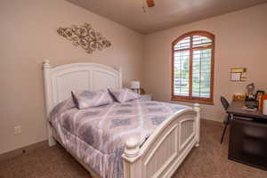 Comfortable secondary bedroom with arched window, ceiling fan, and carpet. Plenty of natural light and room for a full bedroom set plus a workspace.