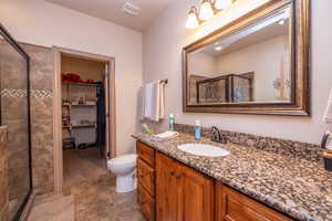 Beautifully appointed ensuite with knotty alder cabinetry, granite countertop, framed mirror, tiled walk-in shower with glass door, and direct access to the walk-in closet. Everything a primary suite should have.