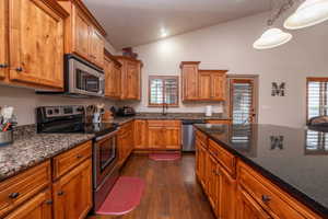 Full view of the kitchen work zone, with stainless range, microwave, dishwasher, and an abundance of counter space. The open sight line into the living areas makes this kitchen the true heart of the home.