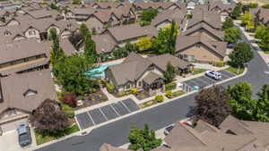 Community clubhouse and sparkling pool shine from above, tucked among mature shade trees with convenient guest and accessible parking nearby.